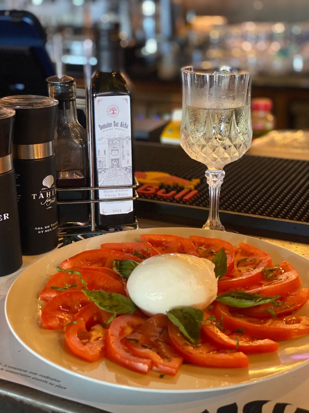Huile d'olive Domaine Dar Aïcha servie à table avec une salade de tomates et mozzarella