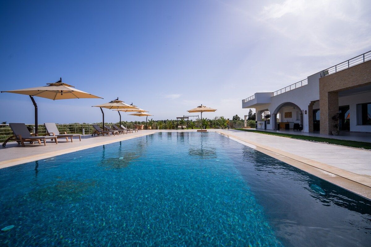 Piscine à débordement avec parasols et vue sur la campagne de Tazarka